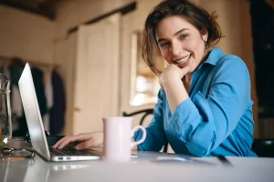 Mulher feliz na mesa com notebook representando cliente pesquisando para criar um site